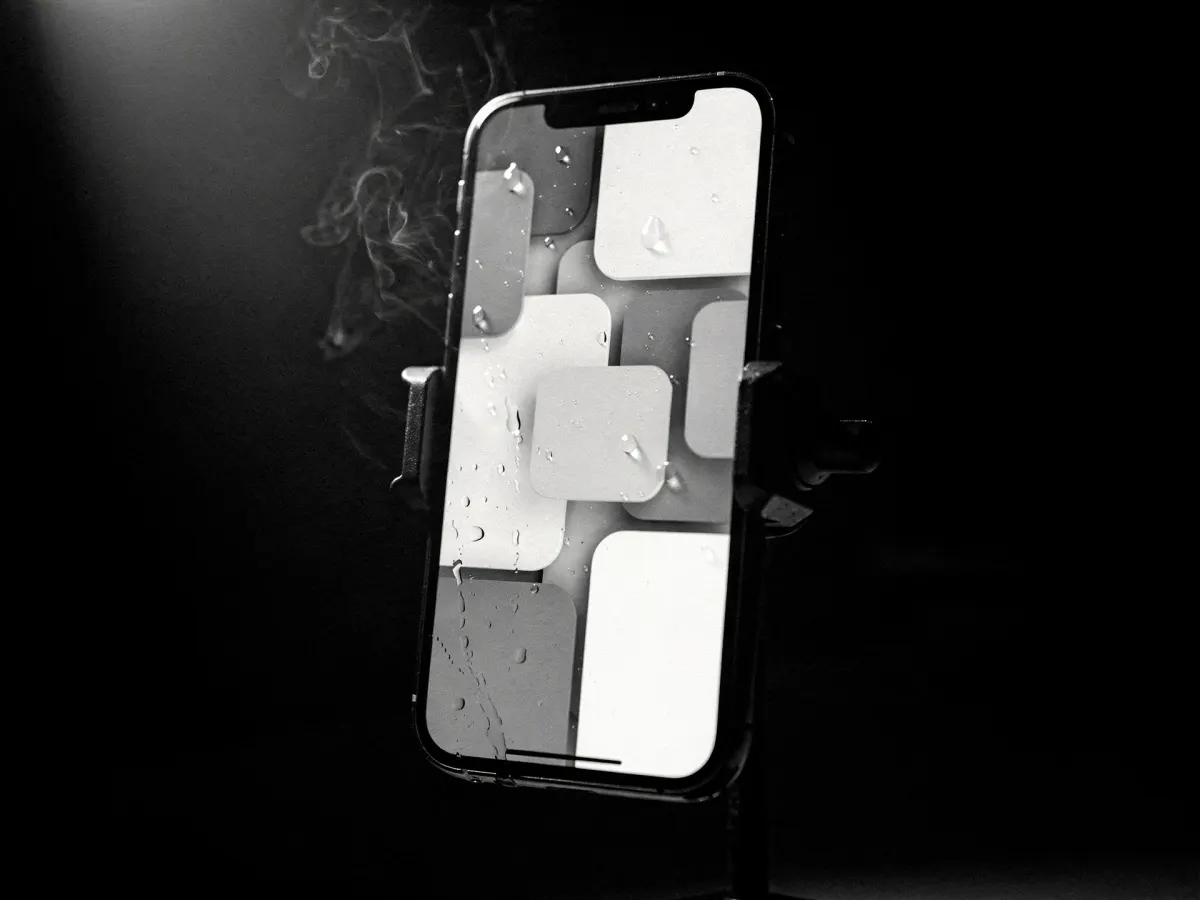 A smartphone in a mounting clamp, isolated in darkness, its screen glowing with bright blocks