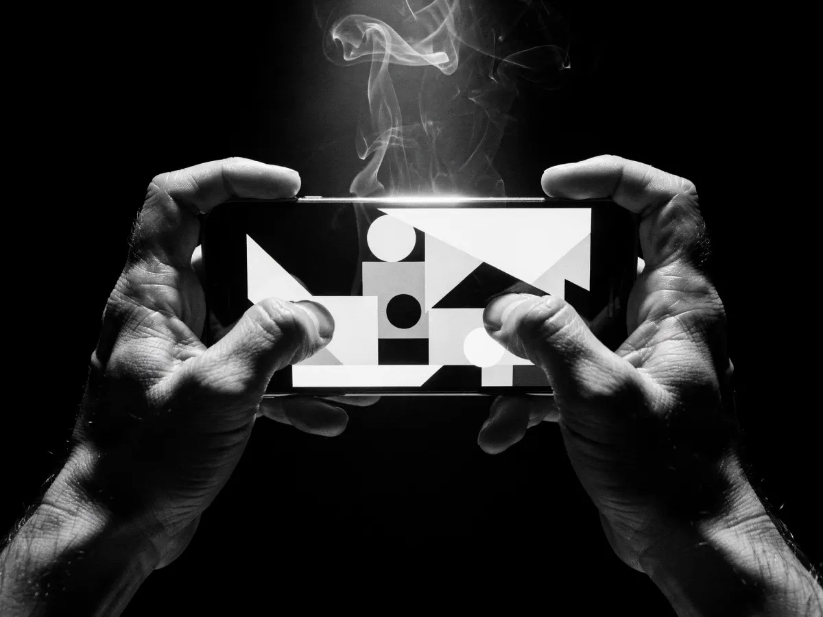 Two hands holding a phone sideways in darkness, the screen lighting the fingers